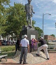 From left, Jonathan Johnson, Eugene Harden and Edward Hamlin, past presidents of the Astoria Beneficial Club, place a wreath at the statue of Bill “Bojangles” Robinson in Jackson Ward last Saturday during the organization’s 46th annual commemoration of the Richmond native and entertainer. In 1933, Mr. Robinson used his own money to purchase a traffic light for the intersection of Leigh and Adams streets after witnessing the dangers young African-Americans faced in trying to cross the busy street. The Astorians placed the statue in his honor at the intersection 46 years ago. (Ava Reaves)