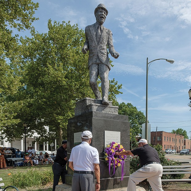 From left, Jonathan Johnson, Eugene Harden and Edward Hamlin, past presidents of the Astoria Beneficial Club, place a wreath at the statue of Bill “Bojangles” Robinson in Jackson Ward last Saturday during the organization’s 46th annual commemoration of the Richmond native and entertainer. In 1933, Mr. Robinson used his own money to purchase a traffic light for the intersection of Leigh and Adams streets after witnessing the dangers young African-Americans faced in trying to cross the busy street. The Astorians placed the statue in his honor at the intersection 46 years ago. (Ava Reaves)