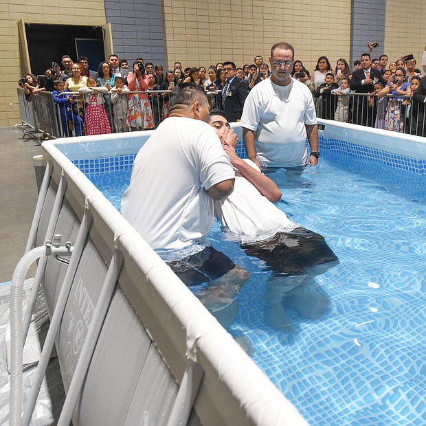 Attendants perform one of several baptisms last Saturday during the Jehovah’s Witnesses regional convention at the Greater Richmond Convention Center. Thousands of people from Virginia and nearby states attend the denomination’s series of three-day conventions each summer in Downtown. This year’s theme: “Love Never Fails!” Highlights include symposia, song, prayer, films and dramatic Bible readings around the theme. The next gathering in the series will be this Friday through Sunday at the convention center. (Clement Britt)