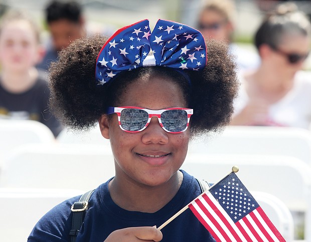 Star-Spangled Celebration:
A youngster with Deborah De Los Santos’ summer camp group waves Old Glory at the Fourth of July ceremony to swear in new U.S. citizens at the Virginia Museum of History & Culture on Richmond’s Arthur Ashe Boulevard. (Regina H. Boone/Richmond Free Press)
