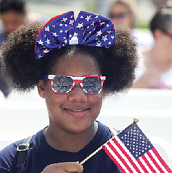 Star-Spangled Celebration
A youngster with Deborah De Los Santos’ summer camp group waves Old Glory at the Fourth of July ceremony to swear in new U.S. citizens at the Virginia Museum of History & Culture on Richmond’s Arthur Ashe Boulevard. (Regina H. Boone/Richmond Free Press)