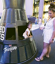 Out of this world/
 Harper Miller peers out from her perch in a replica of Friendship 7, the Mercury capsule in which astronaut John H. Glenn Jr. became the first American to orbit the Earth in February 1962. The youngster was visiting the Science Museum of Virginia with her mom, Kali Miller, and other family members last Saturday as part of the 50th anniversary celebration of the Apollo 11 landing on the moon.