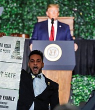 Fairfax Delegate Ibraheem Samirah unfurls a sign in protest during President Trump’s keynote speech Tuesday at the 400th anniversary commemoration in Jamestown.