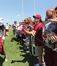 Adrian Peterson, a star running back for the Washington NFL team, strides past fans after a practice session.