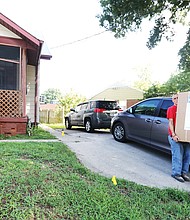 REAL LIFE founder Sarah Scarbrough waits to hold the door as Ryan Riggs, left, a case manager at the home for men in recovery, and Leander Watkins, a resident at the men’s home, carry a new bathroom vanity inside for the new women’s recovery house in South Side.