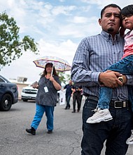 Ivan Flores and his son Derek, 4, pose Tuesday near the site of the Walmart shooting in El Paso.