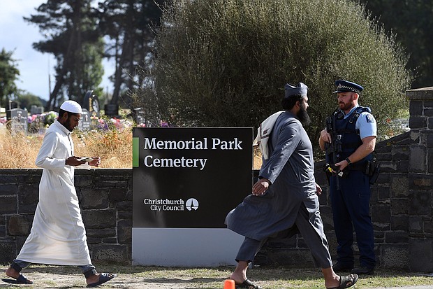 An armed policeman keeps watch as mourners arrive to attend funerals for victims killed in the mosque massacre in Christchurch, New Zealand.