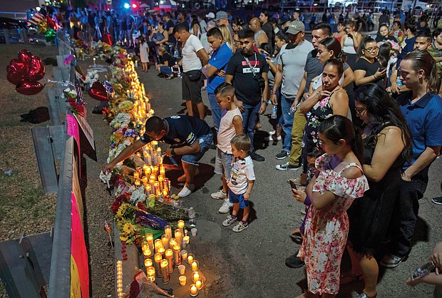 People gather at a memorial for the victims of last Saturday’s massacre at a Walmart in El Paso, Texas, where a gunman shot and killed 22 people and wounded 25 others.