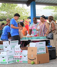 Kevin Alvarado with Urban Harvest assists customers with purchases of fresh fruits and vegetables at the Northeast Community Farmers Market, which held its grand opening on Saturday, Aug. 17 at Kashmere Gardens Elementary, 4901 Lockwood.