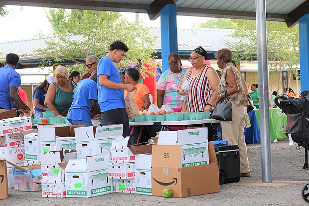 Kevin Alvarado with Urban Harvest assists customers with purchases of fresh fruits and vegetables at the Northeast Community Farmers Market, which held its grand opening on Saturday, Aug. 17 at Kashmere Gardens Elementary, 4901 Lockwood.
