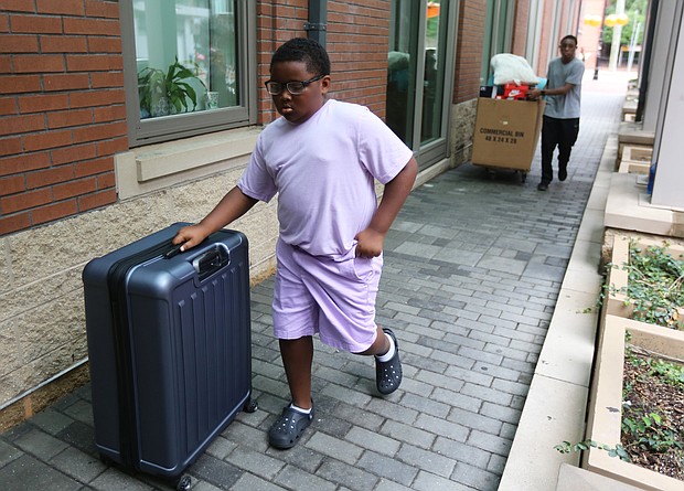 Cityscape: Slices of life and scenes in Richmond/Noah McKay, 11, of Charlotte, N.C. and Desmond Baah, 17, provided the muscle to move a big suitcase and a large box filled with shoes, clothes and other essentials for student life. The student move-in at VCU mirrored similar activity this month at Virginia Union University and the University of Richmond as new and continuing students prepared for the start of classes. (Regina H. Boone/Richmond Free Press)