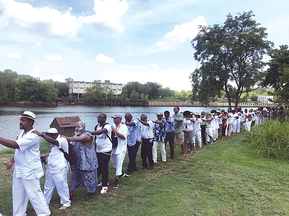 A line of people marches along a portion of the Richmond Slave Trail beside the James River on their way ...