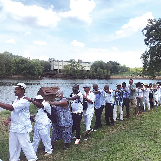 A line of people marches along a portion of the Richmond Slave Trail beside the James River on their way from the Old Manchester docks to Downtown. The walk on Aug. 20 was led by Janine Y. Bell of the Elegba Folklore Society and was symbolic of the many slave coffles in Richmond, which was one of the largest markets for the sale of enslaved people before the end of the Civil War. The walk was one element of the three-day Black Lives Global Summit that the Connecticut-based Community Healing Network sponsored. The summit, held largely at Virginia Union University in concert with other events related to the 400th anniversary of the forced arrival of the first Africans in English North America, focused on providing emotional and psychological healing from the lingering impact of slavery and included a range of speakers focusing on the past, present and future for people of African descent. (Regina H. Boone/Richmond Free Press)