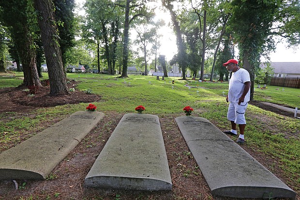 Tracy Richardson of Hampton looks at some of the marked gravesites at the Tucker Family Cemetery nestled in a residential area at 1 Sharon Court in Hampton. The cemetery holds the descendants of William Tucker, the first African-American born in the English colony of Virginia in 1624. According to records, William Tucker was the child of Anthony and Isabella, two of the first Africans brought to Virginia in 1619. (Regina H. Boone/Richmond Free Press)
