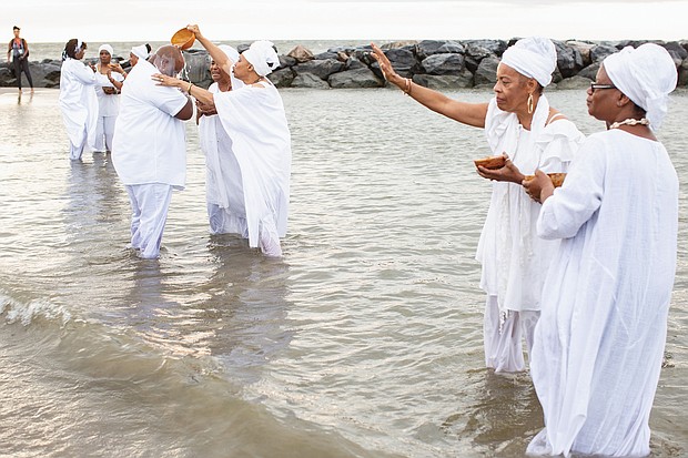 Queen mothers from the Institute of Whole Life Healing in Kentucky anoint participants at a sunrise cleansing and healing ceremony at Buckroe Beach in Hampton as part of the 400th anniversary commemoration of the first Africans landing in English North America.