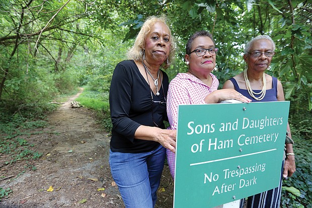From left, Diane W. Jones and her sister, Carolyn W. Moten, and cousin Linda T. Nash stand in front of the sign for the overgrown cemetery in Henrico County where their relatives are buried and which they are working to restore.
