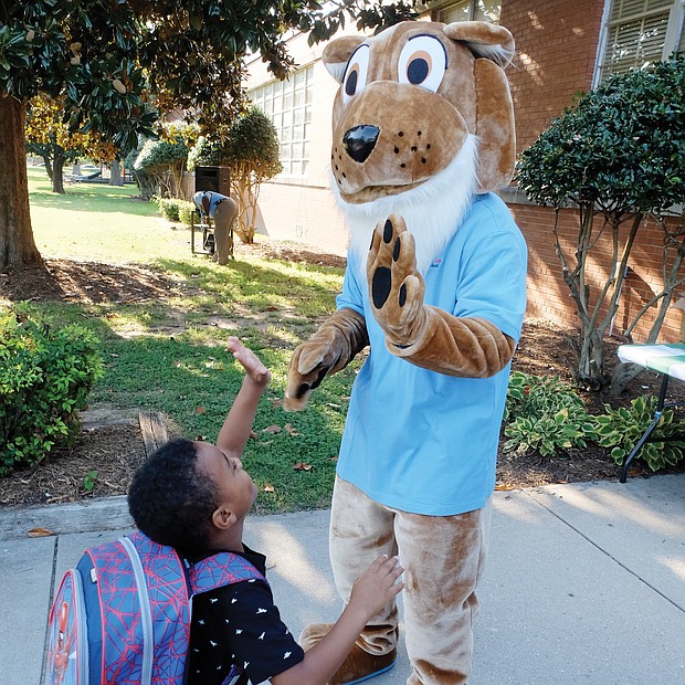 Nehemiah Wright, 5, high fives the cougar mascot at John B. Cary Elementary School as he arrives Tuesday, eager to get the new school year started.