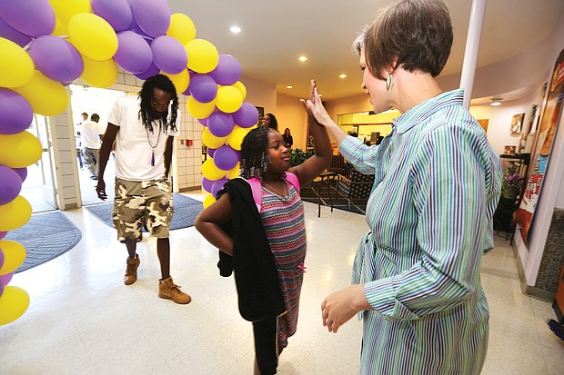 Walking through a welcome arch of balloons at Westover Hills Elementary School, third-grader Kemdyl Grevious is greeted with a high five from Principal Allison El Koubi, as she and her father, Dylan Grevious, arrive Tuesday for the opening day.