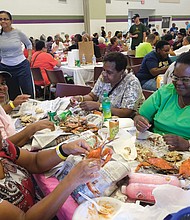 A real feast/ Hundreds of people are in crab heaven at the all-you-can-eat Crab Feast & Fish Fry held last Saturday by the Men of St. Peter’s Episcopal Church at Peter Paul Development Center in the East End. The annual event benefits the outreach and community center that serves seniors and after-school programs for youngsters. Enjoying the meat they picked from crabs are, seated clockwise from left, Rhonda Thorpe, Delores Key, Catherine Rob- inson and Nicole Robinson. (Sandra Sellars/Richmond Free Press)