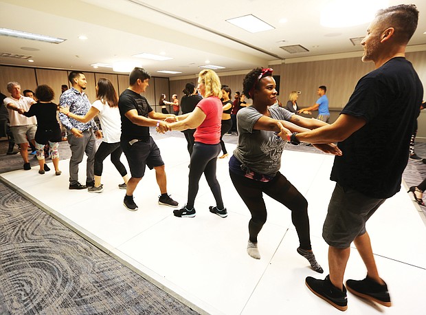 No do-si-do here/Participants watched them demonstrate central bachata, then practiced the moves as they rotated partners. At far right, Nikkia Parker of Richmond and Noel Aguilar of Williamsburg share a dance as they practice moves during a workshop last Saturday. (Regina H. Boone/Richmond Free Press)