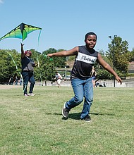 High flier! Kyan Nixon, 9, races to head off a hard landing by the kite launched by his mother, Jess Nixon, during the low winds last Saturday at the World Heritage Festival and Festival of Kites on Brown’s Island in Downtown. The waterfront festival drew kite fliers, a variety of artists and vendors offering wares and representatives of nonprofit and other organizations offering information. (Sandra Sellars/Richmond Free Press)