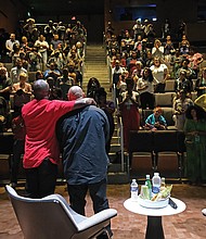 The audience at the Afrikana Independent Film Festival gives a standing ovation last Saturday to Raymond Santana, center, after the screening of the documentary “The Central Park Five.” Mr. Santana, who was exonerated in the case after spending five years in prison, talked about his experience following the film. He is embraced by Todd Waldo, adviser for the film festival, while moderator Zoe Spencer, a sociology professor at Virginia State University, looks on.