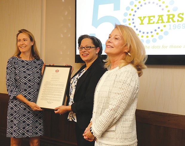 Daily Planet board chair Elizabeth Roark, left, is presented a General Assembly resolution recognizing the Daily Planet’s 50 years of service to people in Central Virginia from state Sen. Jennifer McClellan of Richmond. Beth Merchant, chief executive officer of the Daily Planet, right, also participated in the presentation held Aug. 7 at the organization’s West Grace Street headquarters.