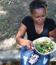 Vegan for the soul/Aranda Goodwin of Virginia Beach sits in the shade to enjoy a raw vegan salad from Goatocado, a restaurant in The Fan that had a booth at the event. In addition to food, the block party featured cooking demonstrations, speakers, music and dancing. (Regina H. Boone/Richmond Free Press)