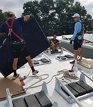 Installers put a solar panel in place on the roof of a new home in the 1200 block of West Leigh Street.