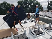 Installers put a solar panel in place on the roof of a new home in the 1200 block of West Leigh Street.