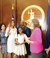 Kemba Smith Pradia, center, is sworn in as a member of the Virginia Parole Board on Sept. 26, by Kelly Thomasson, state secretary of the commonwealth, as her daughter, Phoenix, holds the Bible. Witnessing the ceremony are, from left, her parents, Gus and Odessa Smith; her husband, Patrick Pradia; and Brian Moran, state secretary of public safety and homeland security.