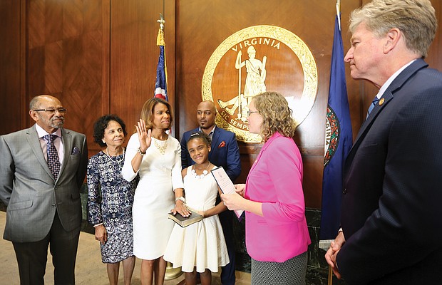 Kemba Smith Pradia, center, is sworn in as a member of the Virginia Parole Board on Sept. 26, by Kelly Thomasson, state secretary of the commonwealth, as her daughter, Phoenix, holds the Bible. Witnessing the ceremony are, from left, her parents, Gus and Odessa Smith; her husband, Patrick Pradia; and Brian Moran, state secretary of public safety and homeland security.