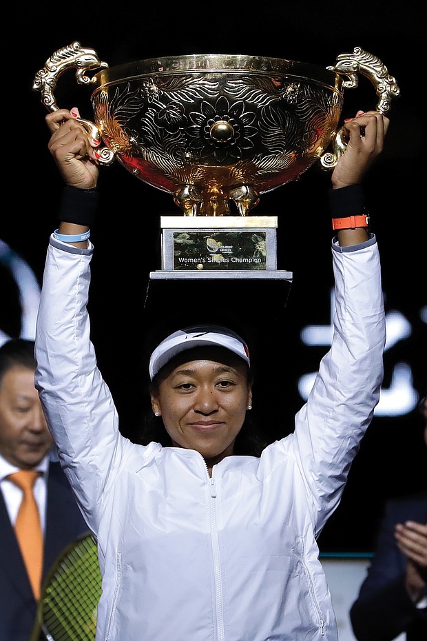 Naomi Osaka lifts high her winner’s trophy after defeating Ashleigh Barty of Australia in the women’s final at the China Open tennis tournament in Beijing on Oct. 6.