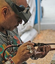 Lots of music, lots of folk/Richmond’s Downtown riverfront came alive with people and music last weekend as thousands of people turned out for the Richmond Folk Festival. Emanuel Carona of Third Generation Jewelers in Milwaukee, one of scores of artisans and artists displaying their work during the festival, carefully crafts a bracelet. (Sandra Sellars/Richmond Free Press)