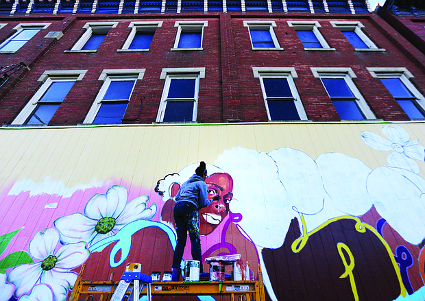 Cityscape: Slices of life and scenes in Richmond-Artist Austin Miles of Petersburg puts the finishing touches last week on this new mural that now decorates Max Market, 1125 Hull St. She is contributing the fine details to the mural that began with a community paint day Oct. 5. The mural is the first of a planned series titled “Brown Girl Narratives” that Kristal Brown, founder and leader of Black Women Cache LLC, is spearheading. This and other murals will help fulfill the goal of the organization, Ms. Brown said, which is “to highlight the lived experiences of black women through media and visual arts.” Next year, the Virginia Commonwealth University doctoral student plans to release a coffee table book focusing on black women and hold other events. (Regina H. Boone/Richmond Free Press)