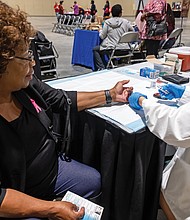Essie Sykes, right, has her blood sugar measured by Celina Hu of the Virginia Commonwealth University School of Pharmacy.
