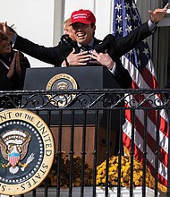 First Lady Melania Trump laughs as President Trump embraces Washington Nationals catcher Kurt Suzuki, who donned a MAGA hat Monday during a White House event to honor the World Series champions.