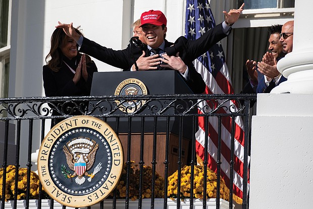 First Lady Melania Trump laughs as President Trump embraces Washington Nationals catcher Kurt Suzuki, who donned a MAGA hat Monday during a White House event to honor the World Series champions.