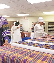 Richmond Delegate Delores L. McQuinn, a minister and chair of the Richmond Slave Trail Commission, prayerfully puts her hand on the Kente cloth covering one of 17 boxes of human remains found in 1994 in a well on Virginia Commonwealth University’s medical campus. The remains, which were returned to Richmond during a ceremony on Monday, will be stored by the state Department of Historic Resources while planning for an appropriate burial and memorial continues.