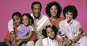 This photo shows Bill Cosby portraying Dr. Cliff Huxtable with his television family in the long-running and hugely popular hit “The Cosby Show.” The show was created by Mr. Cosby.