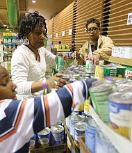 Chandle Brooks, 7, helps to organize canned vegetables with his aunt, Charlene Taylor, center, and Tawana Ferguson at Operation Harvest, a community Thanksgiving food distribution effort launched three years ago by St. Paul’s Baptist Church. This is the third year for the effort that has drawn support from dozens of organizations and companies across the area and more than 400 volunteers.