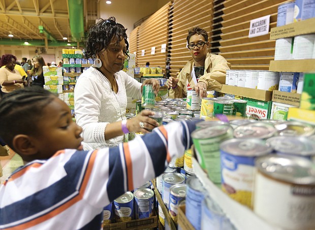 Chandle Brooks, 7, helps to organize canned vegetables with his aunt, Charlene Taylor, center, and Tawana Ferguson at Operation Harvest, a community Thanksgiving food distribution effort launched three years ago by St. Paul’s Baptist Church. This is the third year for the effort that has drawn support from dozens of organizations and companies across the area and more than 400 volunteers.