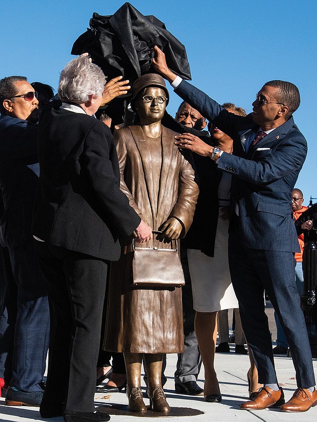 Montgomery, Ala., Mayor Steven Reed, right, and Alabama Gov. Kay Ivey, front left, work with others to unveil the statue of civil rights icon Rosa Parks in downtown Montgomery last Sunday, the anniversary of her 1955 arrest for not giving up her seat on a public bus.