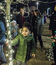 Eden Boyce, 5, hangs on to a tree decorated with lights during the festivities.