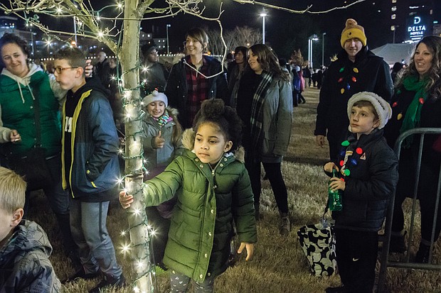 Eden Boyce, 5, hangs on to a tree decorated with lights during the festivities.