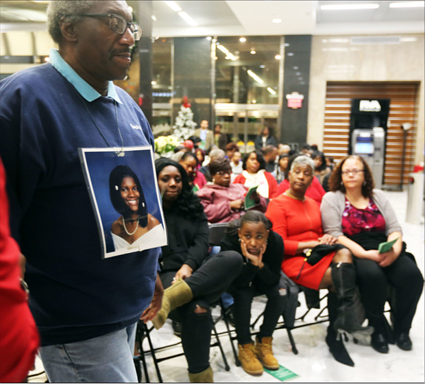 John Burnley of Richmond, below, wears a photo of his late daughter, Juanita Burnley, during the Coalition Against Violence’s 29th Annual Holiday Memorial Service to remember those who lost their lives to violence in the city. Relatives, friends and supporters mourning lost loved ones who were victims of violence at- tended the Dec. 12 ceremony held in the lobby of Richmond City Hall. Participants wrote the names of their loved ones on red ribbons that
were placed around the statue, “River of Tears,” that stands situated in City Hall. Mr. Burnley’s daughter was murdered by her boyfriend in No- vember 2007, and he has annually attended the memorial started by Linda Jordan to help family members with their grief and loss through the holidays.
