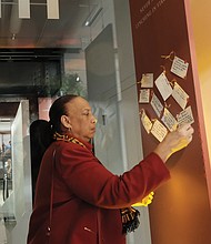 Former Richmond Judge Birdie H. Jamison, right, places a note with her thoughts about the exhibit on a public thought board.