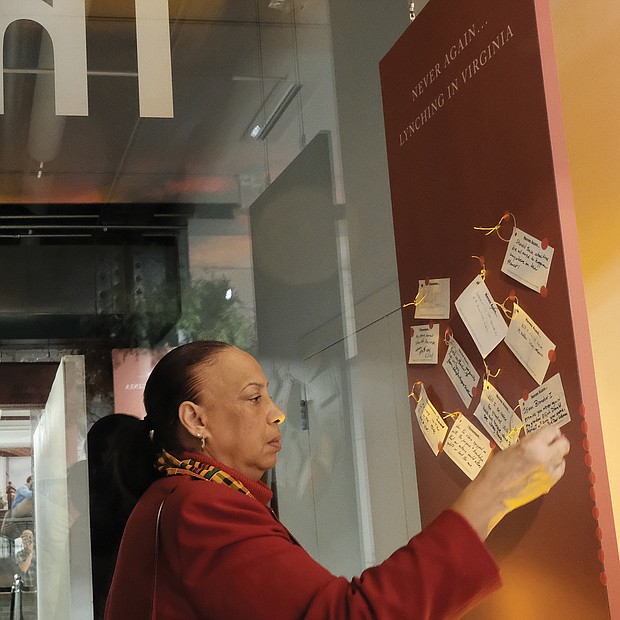 Former Richmond Judge Birdie H. Jamison, right, places a note with her thoughts about the exhibit on a public thought board.