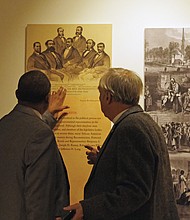Rev. Sylvester Turner and the Rev. Ben Campbell, both of whom serve on the Richmond Slave Trail Commission discuss one of the panels in the exhibit.