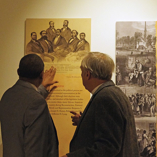 Rev. Sylvester Turner and the Rev. Ben Campbell, both of whom serve on the Richmond Slave Trail Commission discuss one of the panels in the exhibit.